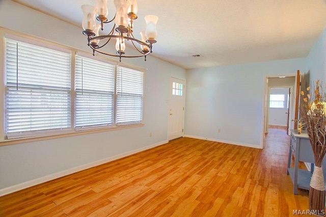 unfurnished room with light hardwood / wood-style floors and a notable chandelier