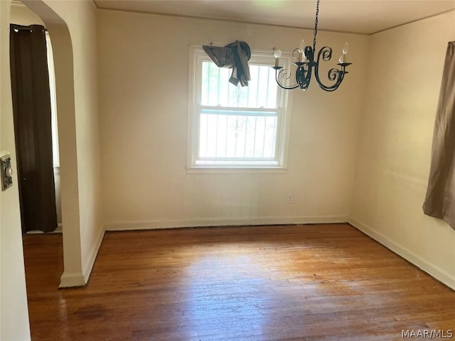 unfurnished dining area featuring wood-type flooring and an inviting chandelier