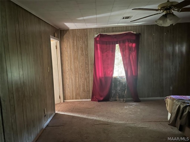 interior space featuring ceiling fan, carpet, and wood walls