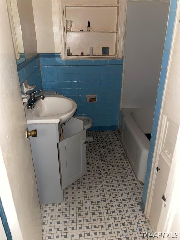 bathroom with vanity, toilet, tile walls, and a washtub