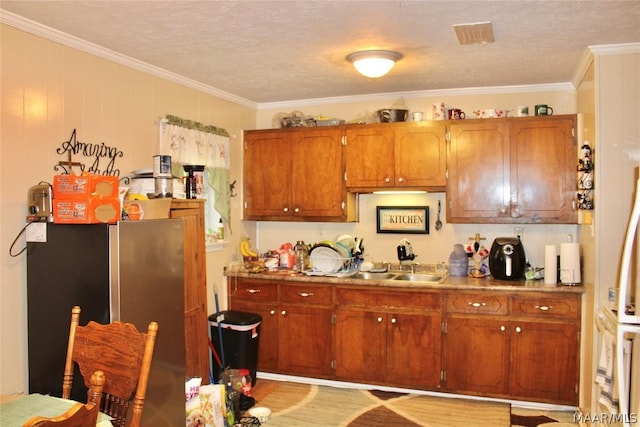 kitchen featuring sink, a textured ceiling, and ornamental molding