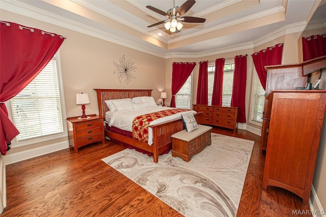 bedroom featuring dark wood-type flooring, crown molding, a raised ceiling, and multiple windows