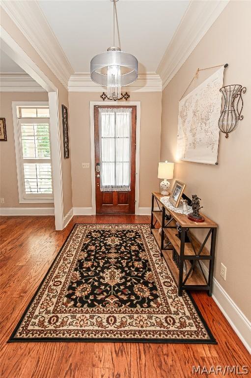 foyer with an inviting chandelier, hardwood / wood-style flooring, and ornamental molding