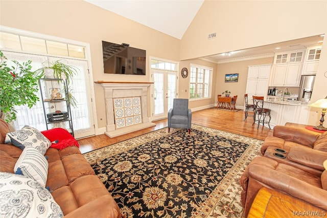 living room with hardwood / wood-style flooring, sink, high vaulted ceiling, and french doors