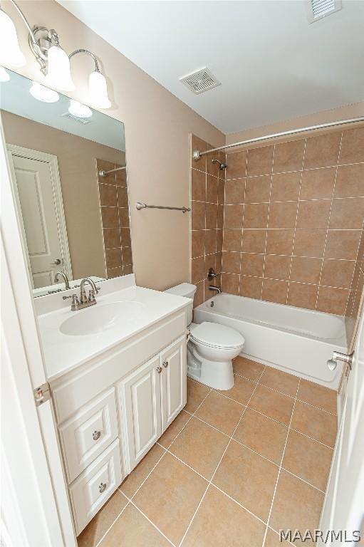 full bathroom featuring tile patterned flooring, vanity, tiled shower / bath combo, and toilet