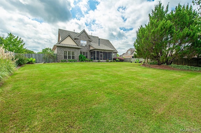 rear view of property featuring a yard and a sunroom