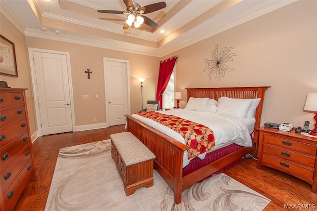 bedroom with ornamental molding, wood-type flooring, and a tray ceiling