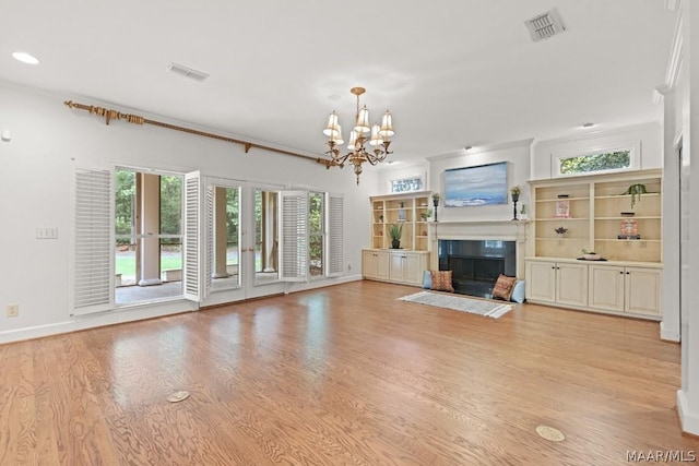 unfurnished living room featuring crown molding, plenty of natural light, light wood-type flooring, and a notable chandelier