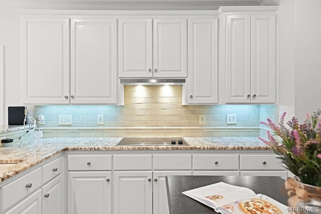 kitchen with white cabinets, light stone countertops, black electric cooktop, and tasteful backsplash