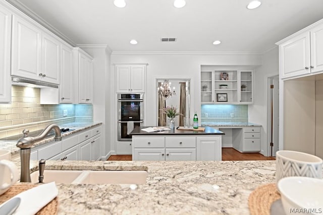 kitchen with stainless steel double oven, light stone counters, white cabinetry, and sink