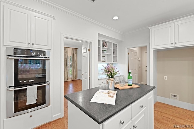 kitchen with stainless steel double oven, crown molding, built in features, white cabinets, and light hardwood / wood-style floors