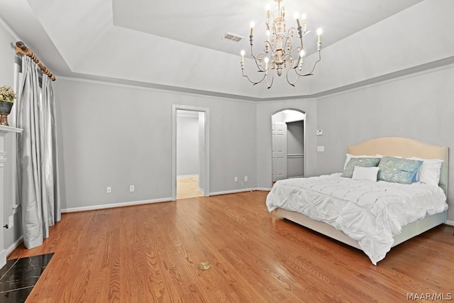 bedroom featuring a chandelier, wood-type flooring, and a raised ceiling