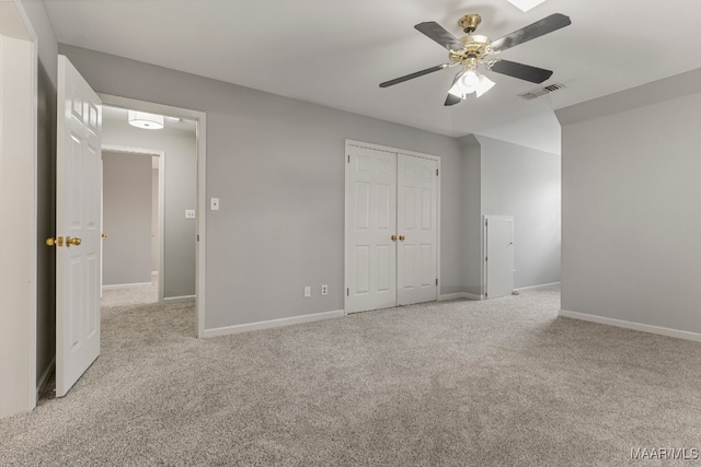 unfurnished bedroom with a closet, ceiling fan, and light carpet