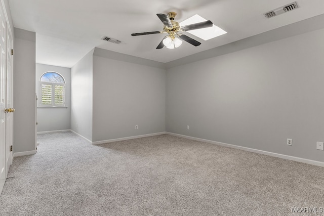 carpeted empty room with ceiling fan and a skylight