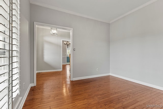 empty room with crown molding, hardwood / wood-style floors, and a notable chandelier