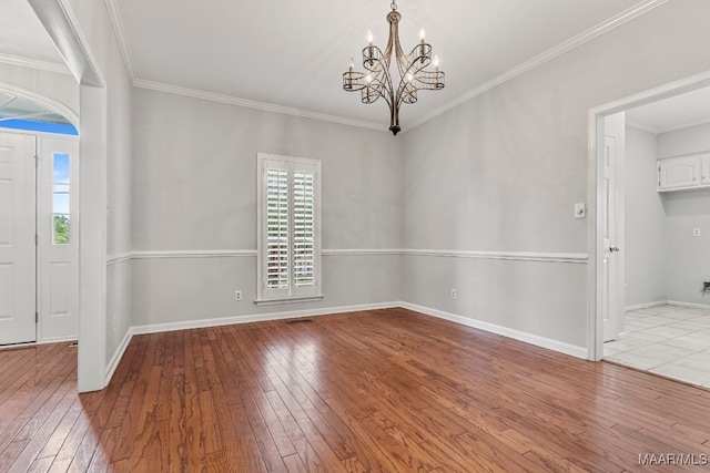 spare room featuring a chandelier, light hardwood / wood-style floors, and crown molding