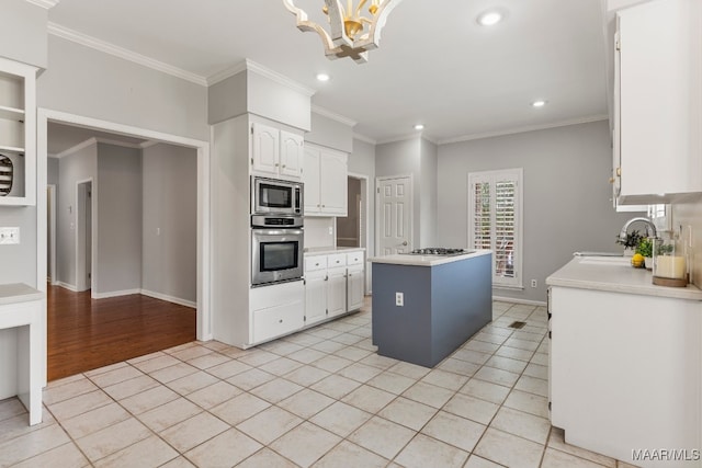 kitchen with a kitchen island, appliances with stainless steel finishes, light hardwood / wood-style floors, sink, and white cabinets