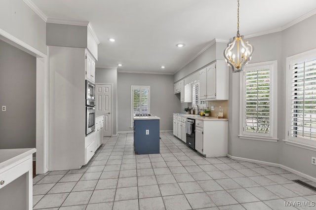 kitchen with an inviting chandelier, pendant lighting, appliances with stainless steel finishes, a center island, and white cabinets