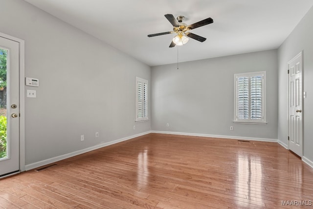 empty room with a wealth of natural light, ceiling fan, and light wood-type flooring