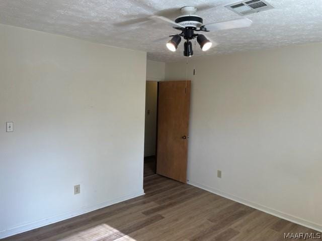 empty room featuring ceiling fan, a textured ceiling, and dark wood-type flooring