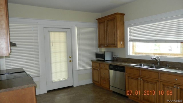 kitchen featuring stainless steel appliances, dark countertops, brown cabinets, and a sink
