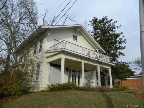 rear view of property featuring a balcony and a yard