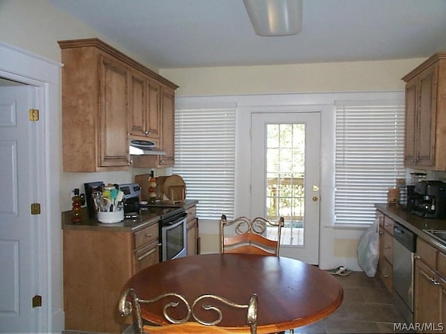 kitchen featuring ventilation hood, stainless steel appliances, dark countertops, and brown cabinets