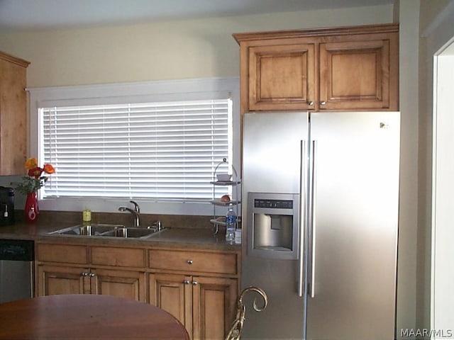 kitchen featuring dark countertops, brown cabinets, stainless steel appliances, and a sink