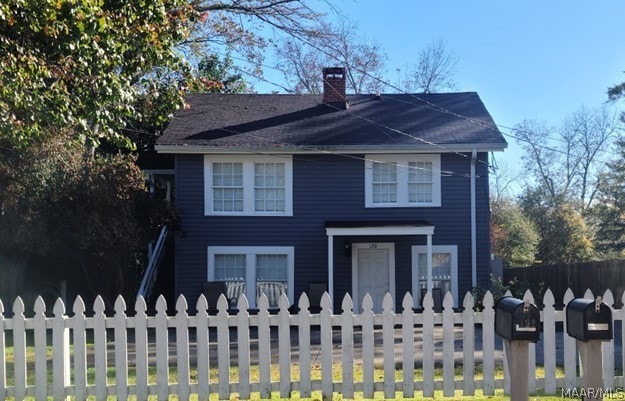 view of front of home with a fenced backyard and a chimney