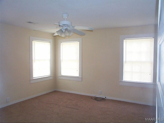 empty room with a ceiling fan, carpet flooring, a wealth of natural light, and baseboards