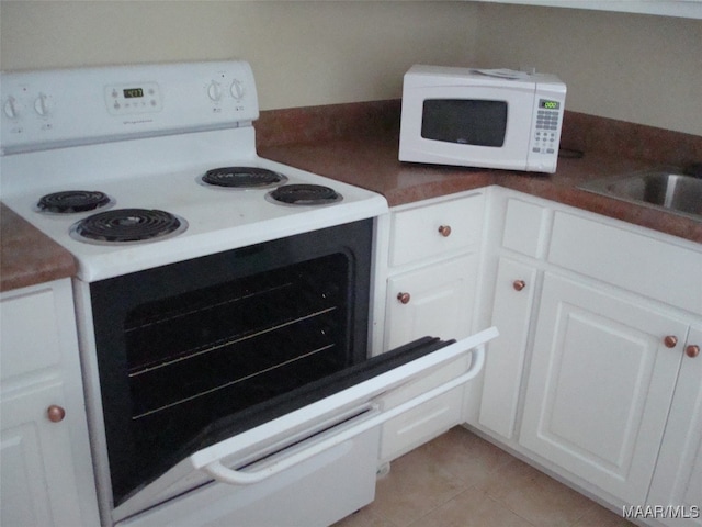 kitchen featuring white cabinets, light tile patterned floors, and white appliances