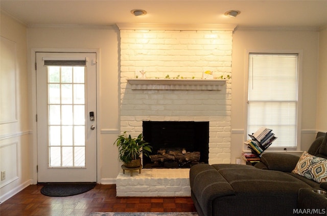 living room with brick wall, ornamental molding, dark parquet flooring, and a brick fireplace