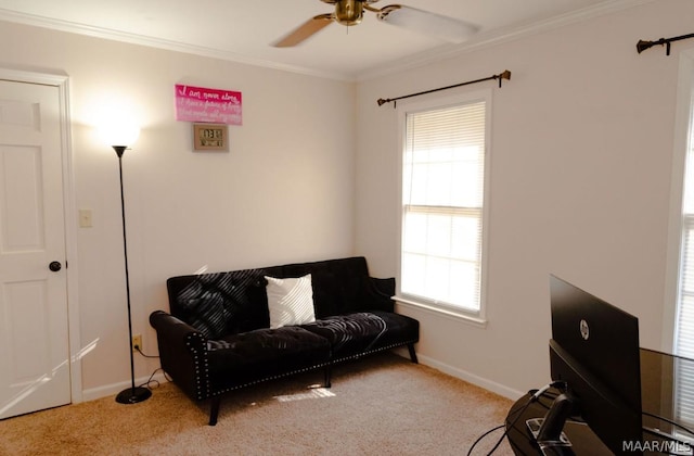 living area featuring baseboards, carpet, ceiling fan, and crown molding