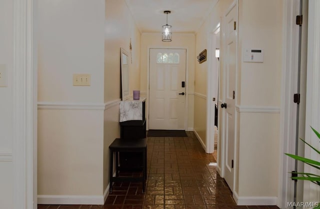 interior space featuring baseboards, crown molding, and brick floor