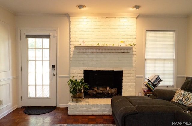 living area featuring plenty of natural light, a fireplace, and ornamental molding