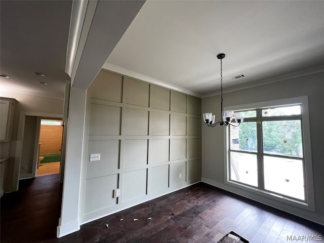 unfurnished dining area with dark wood-type flooring, ornamental molding, and a notable chandelier