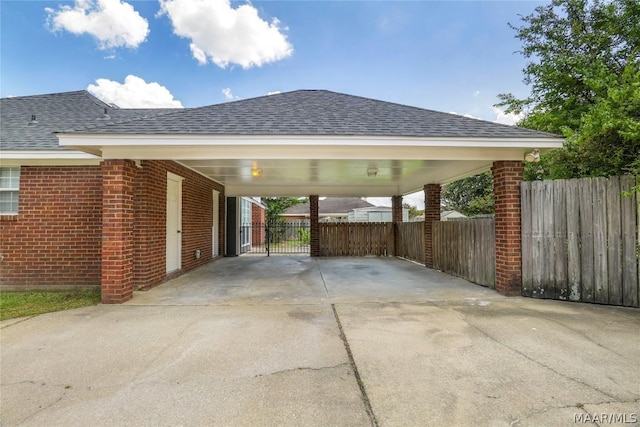 view of parking / parking lot with a carport, concrete driveway, and fence