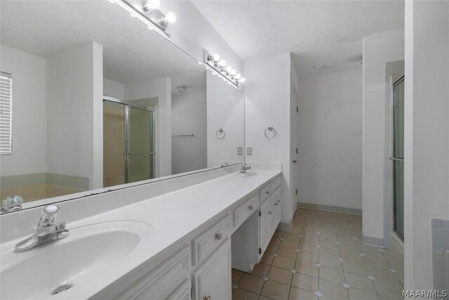 bathroom with a textured ceiling, vanity, and walk in shower