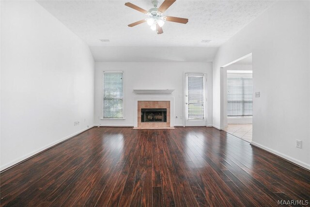 unfurnished living room with a textured ceiling, a tiled fireplace, a wealth of natural light, and vaulted ceiling