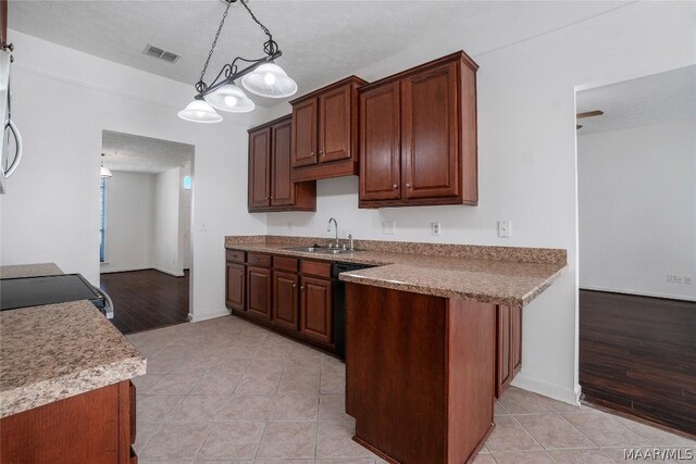 kitchen with a textured ceiling, sink, light tile patterned floors, dishwasher, and hanging light fixtures