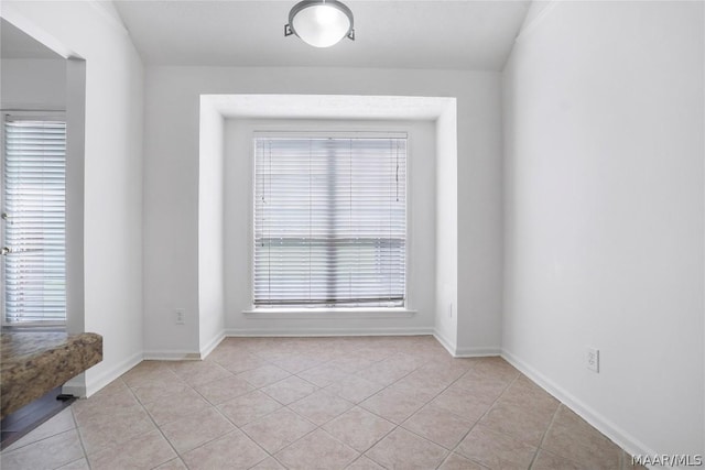 spare room with light tile patterned floors, plenty of natural light, and baseboards