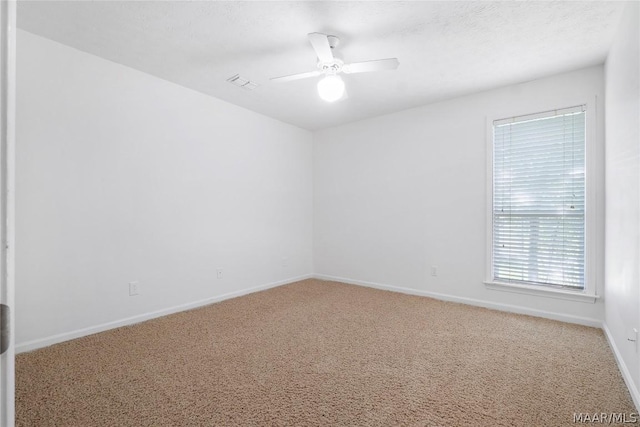 carpeted empty room with baseboards, a textured ceiling, visible vents, and a ceiling fan