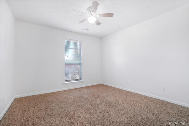 carpeted empty room with ceiling fan, visible vents, and baseboards