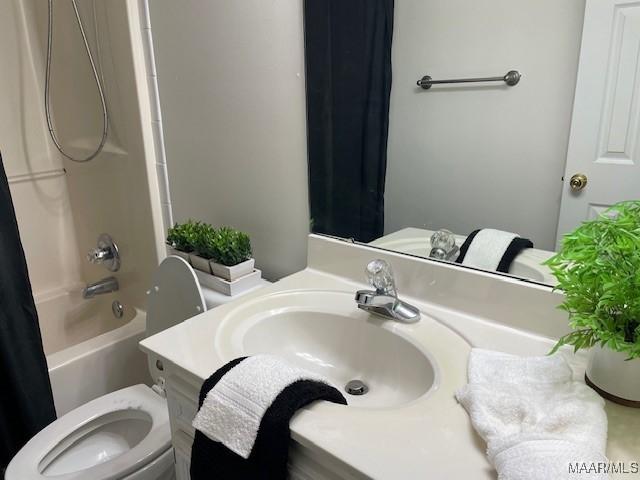 full bath featuring toilet, shower / bathtub combination with curtain, and a sink