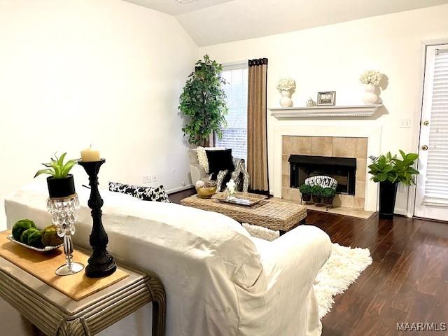 living room with vaulted ceiling, dark wood-type flooring, a fireplace, and baseboards