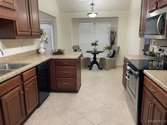 kitchen with light countertops, appliances with stainless steel finishes, a sink, and decorative light fixtures