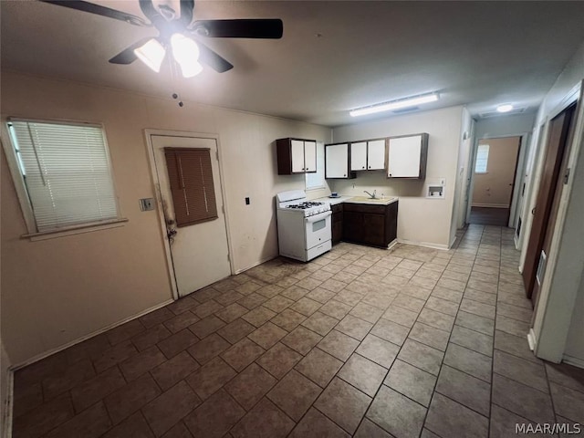 kitchen with ceiling fan, white gas range, and sink