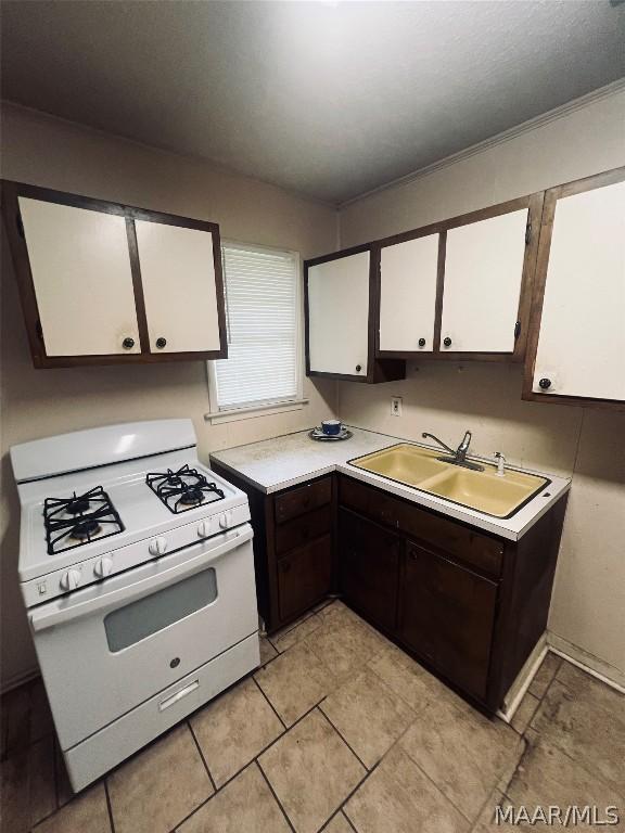 kitchen with white cabinetry, crown molding, white gas range, and sink