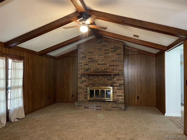 unfurnished living room with vaulted ceiling with beams, a brick fireplace, wooden walls, and carpet floors