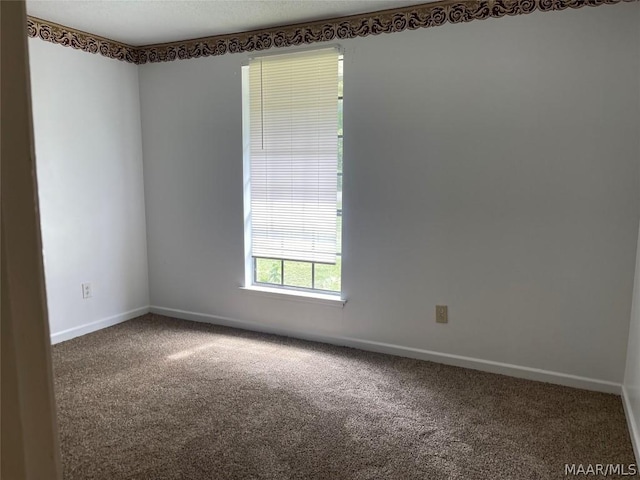 carpeted empty room featuring baseboards